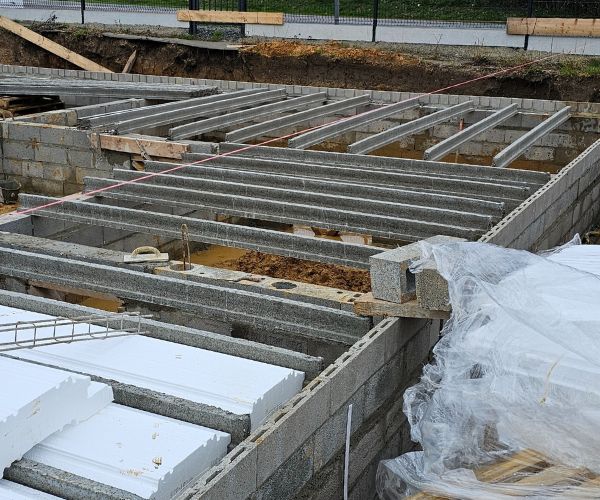 Chantier de construction des fondations en blocs béton et poutrelles