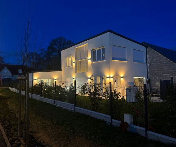 Façade éclairée la nuit avec jardin